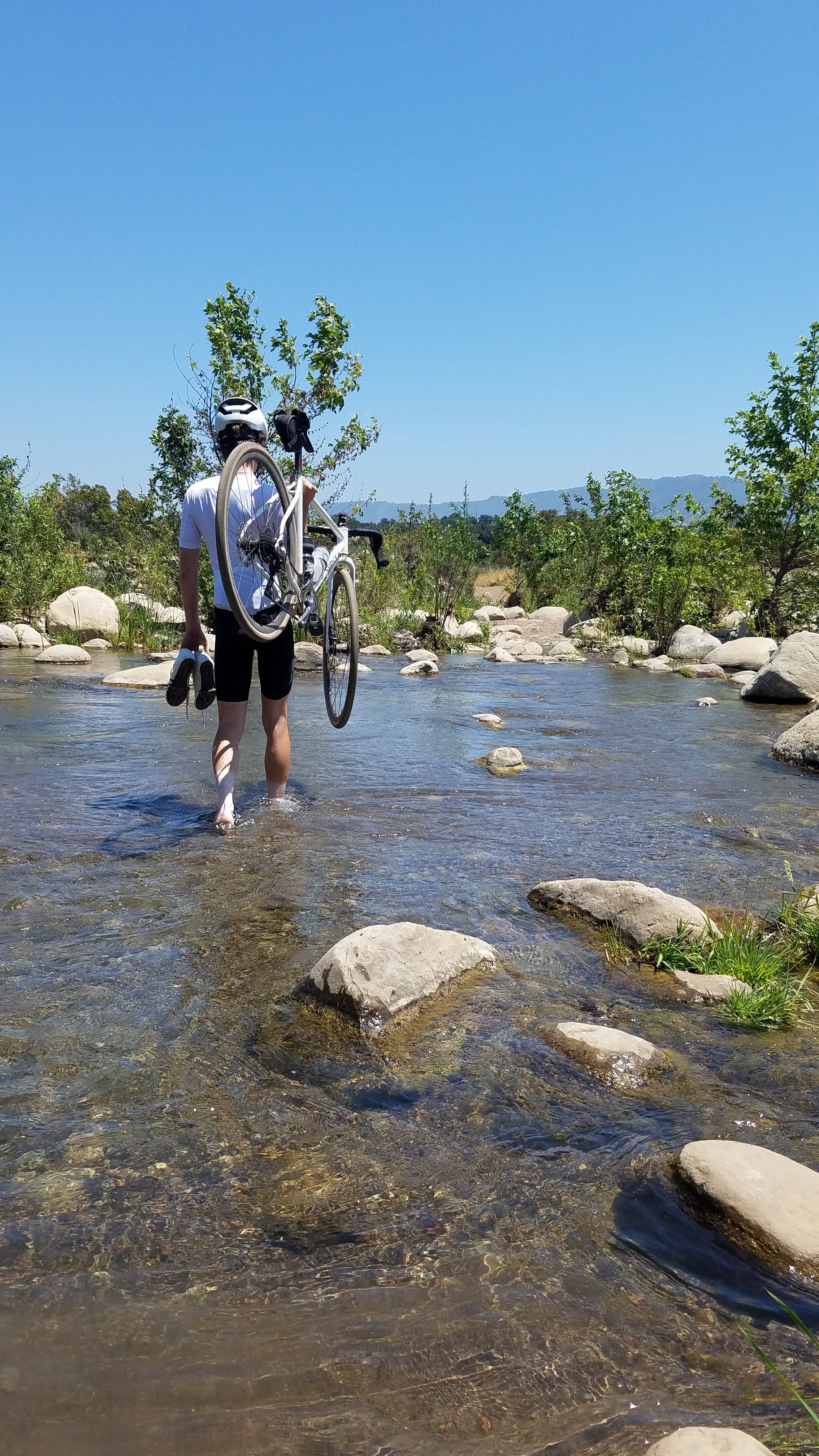 cameron mitchell walking through river with bike